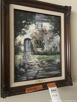 Framed artwork in carved wood frame showing cottage scene with roses and pathway