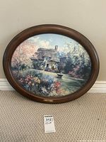 Full view of the oval framed print showing the cottage garden scene and the frame.