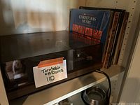 Turntable and albums on shelf with clear dust cover and cardboard album sleeves visible