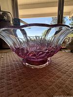 Side view of the vintage glass bowl showing flared rim and color variation from pink to clear.