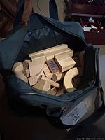 Open carrying bag showing assorted natural wood building blocks with some blue painted details
