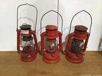 Front view of three red kerosene barn lanterns