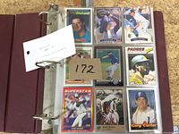 Binder open showing nine baseball cards in plastic sleeves and lot note