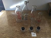 Group shot of five milk bottles and three ink bottles on table