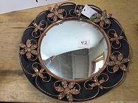 Front view of round convex mirror with decorative metal floral frame