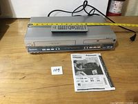 Full view of Panasonic DVD/VCR combo with remote, manual and tape measure