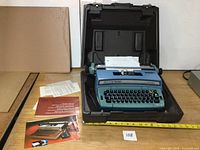 Typewriter in open case with manuals and paperwork visible