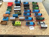 Top view of entire lot showing multiple locomotives and cars on plywood surface