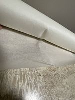 Rolled backing sheet being held showing texture and slight creasing