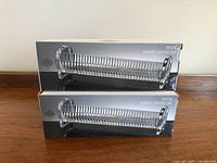 Two boxed crystal cracker trays stacked on top of each other, showing the trays through the packaging.