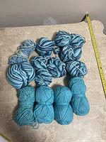 Twelve skeins of yarn laid out on a table, showing different sizes and two main styles: solid colored and multicolored twisted patterns.