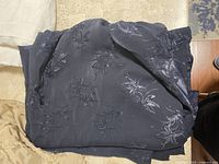 Folded black fabric piece with floral patterns visible in low light.