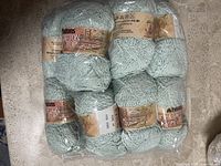 12 rolls of light green Patons Cotton Top yarn wrapped in clear plastic packaging