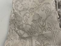 Close-up view of light brown fabric showing detailed floral woven pattern