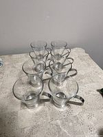 Set of 6 glass espresso cups with stainless steel handles arranged on table