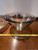 Four heavy glass nesting bowls stacked inside each other, with a tape measure showing approximately 11 inches diameter for the largest bowl.