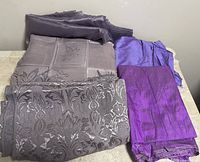 Top view showing five different purple fabric pieces with varied textures and patterns, including sheer and jacquard fabrics.
