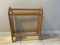 Front view of the handmade solid wood quilt rack showing three horizontal bars for holding quilts and natural wood finish.