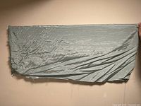 Photo of roll of green fabric spread open showing its texture and color.