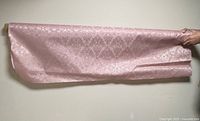 Photo showing entire roll of pink jacquard fabric held horizontally to show length and texture.