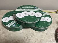 Three round green boxes with holiday-themed ceramic dessert plates inside, unopened and sealed.