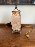 Front view of the small square compact light with fabric shade and ornate metal base on wooden surface