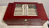 Closed mahogany-style wooden case with glass top showing organized cutlery