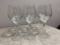 Front angled view of 6 clear wine glasses showing their tulip-shaped bowls and detailed bases with ornate sculpture.