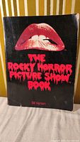 Front cover of The Rocky Horror Picture Show book showing black background with red lips graphic and title in red dripping font.