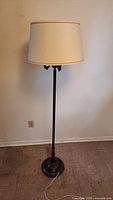 Full view of the lamp with the white fabric shade on top and the tall black metal stand with an antique bronze finish.