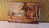 Full view of the oil painting showing a forest road with fall foliage and a water body in the distance