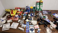 Assortment of plumbing supplies spread on a table showing many plastic pipe fittings, strainers, washers and boxed items.