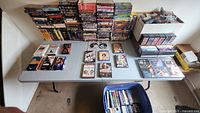 Overview of VHS tapes and DVDs digitally stacked on table and packed in boxes and bins.