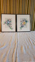 Two framed watercolour paintings on silk by John Chens, each measuring about 8x10 inches, showing intricate floral arrangements in soft colors.