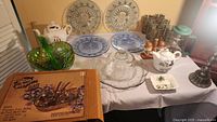 Full view of kitchen glassware including salad bowl set, glass plates, teapot, glassware, and decorative items.