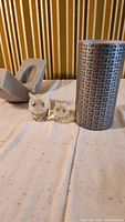 Pair of large and small Swarovski crystal owl figurines displayed next to a measuring tape and patterned container.