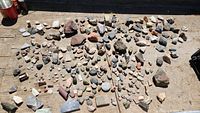 Wide view of the rock collection laid out on a wooden surface showing a variety of sizes and colors.