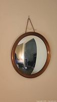 Front view of the round convex mirror hanging on a wall, showing the convex reflection and metal frame.