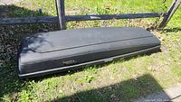 Closed Thule Karrite Galaxy black cargo carrier on grass, showing full side profile length approximately 92 inches
