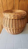 Side angle showing the round shape, woven wicker texture and condition of the basket.