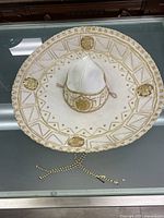 Top-down view of the white felt sombrero with gold embroidery and geometric patterns on the brim.