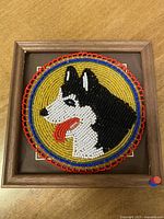 Front view of the circular beaded artwork of a husky dog head framed in wood