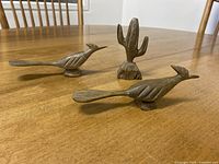 Overview of two roadrunner figurines and one cactus figurine on wooden table
