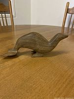Side view of the hand-carved wooden seal figurine showing the natural wood grain and smooth flowing shape with flippers and tail visible.