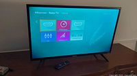 Hisense Roku TV powered on to the home screen showing input sources.
