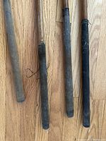 Close-up of four antique golf club grips showing wear and different styles of leather wrapping on wooden shafts.