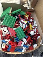 Top view of box filled with assorted colorful Lego bricks and green baseplates