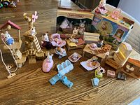 Wide shot showing the entire lot including boxed sets, figures, wooden treehouse playset, furniture, and vehicles on wooden table.