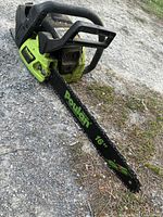 Poulan 16 inch gas chainsaw lying on gravel with visible blade and body