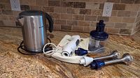 Breville electric kettle and KitchenAid hand mixer with their attachments displayed on countertop.